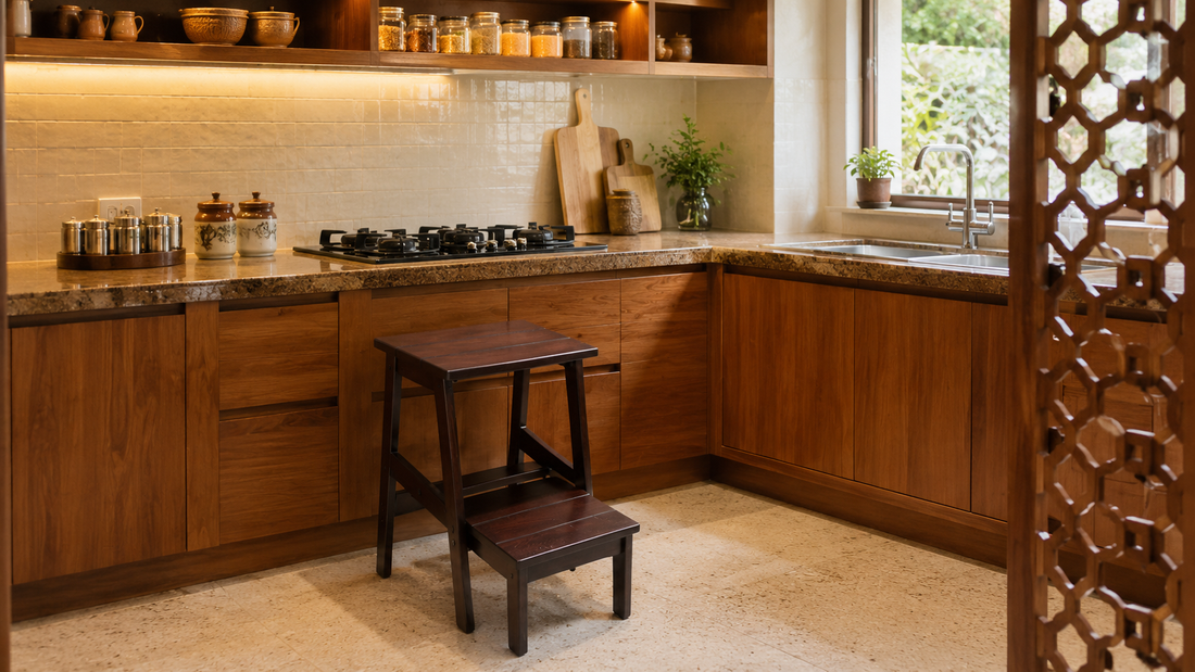 Dark hardwood foldable step stool beside a granite kitchen counter in a warm Indian modular kitchen with wooden cabinets and natural light.