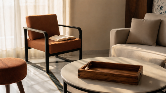 Calm Indian living room on a slow Sunday morning — wrought iron lounge chair, wooden tray with chai cups on coffee table, warm light through sheer curtains — Sinecraft Creations