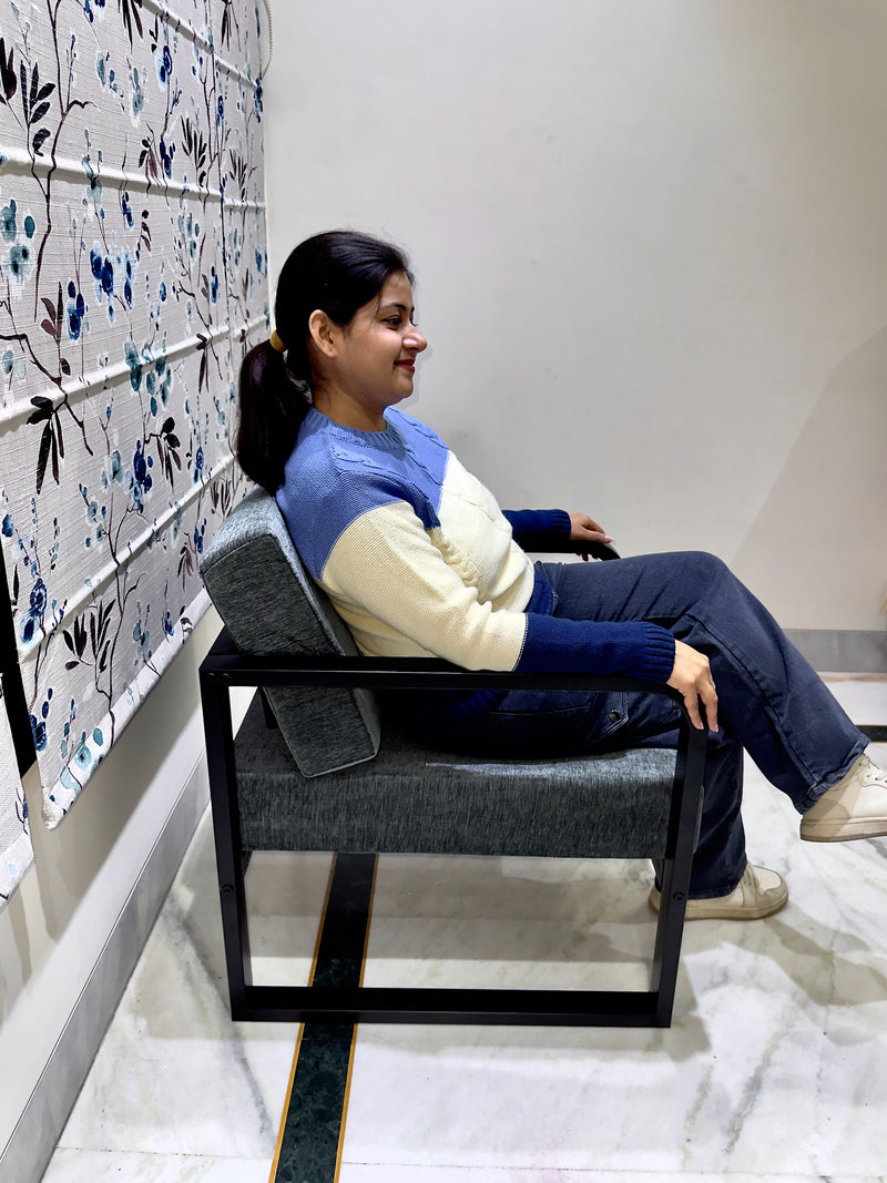 Woman sitting on a modern lounge chair by sinecraft creations against a decorative wall.