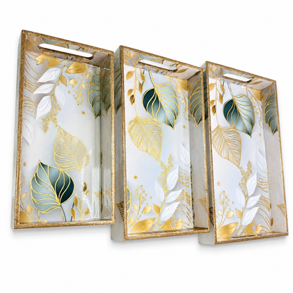Three decorative trays with gold and green leaf patterns on a white background