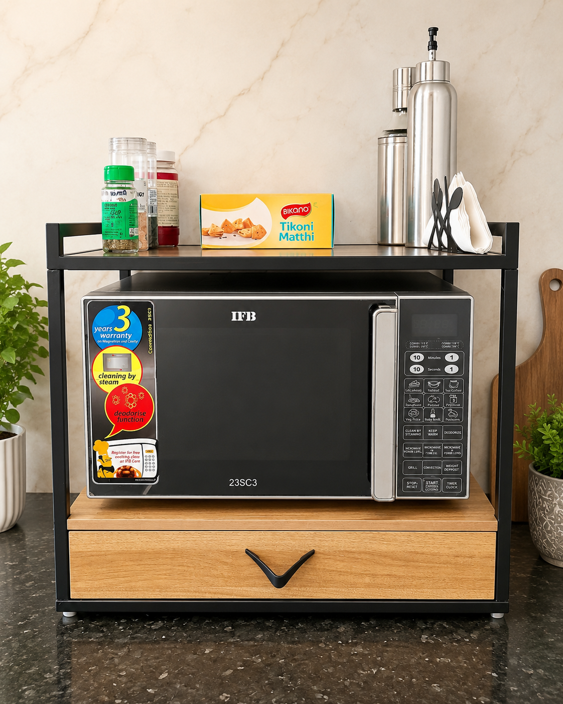 Black metal and wood microwave stand with top shelf and storage drawer placed on a kitchen counter with a 23 litre microwave.
