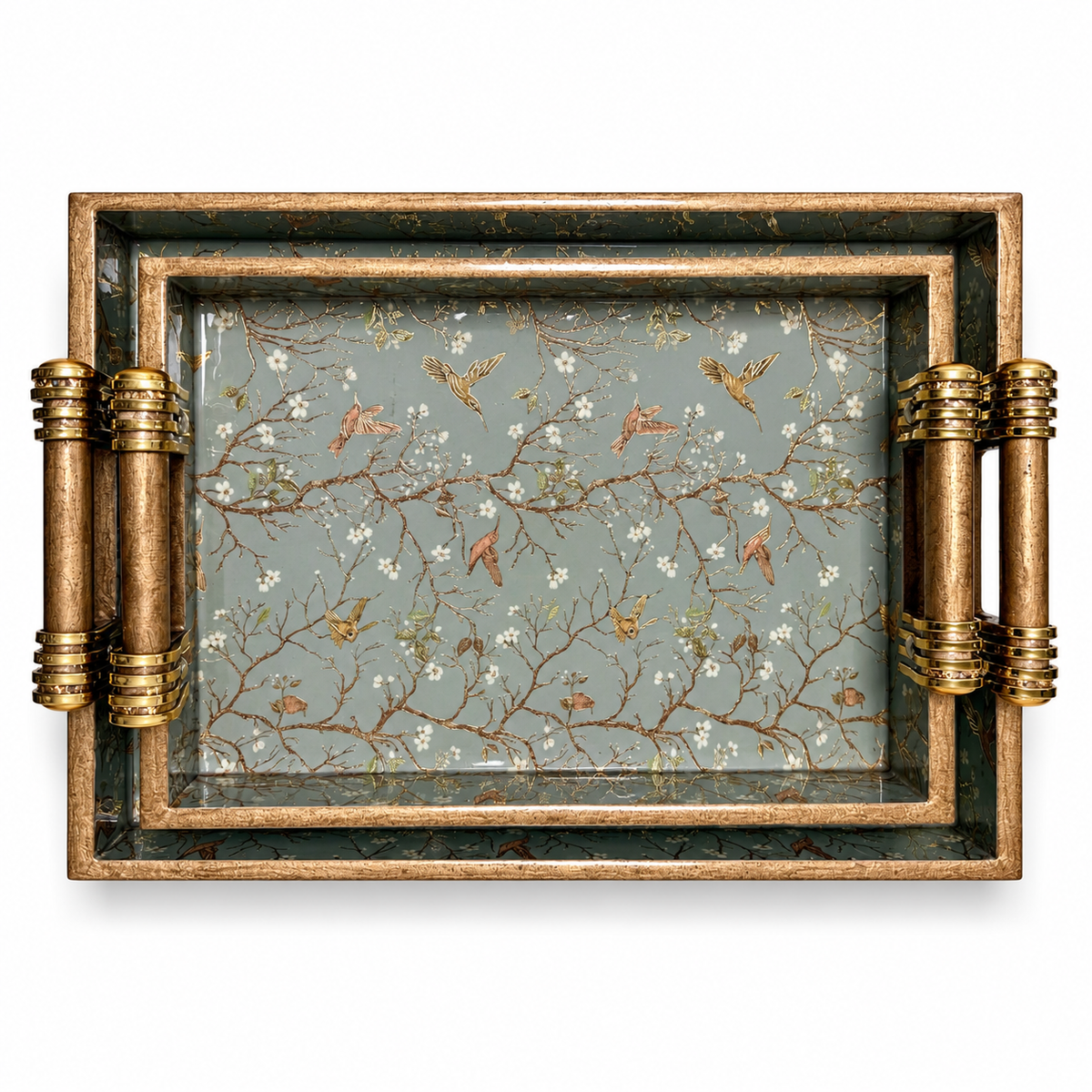 Top view of two nested wooden serving trays with sage green bird and floral patterns and gold-accented handles on a white background.
