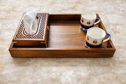 Wooden tray with tissue box and decorative mugs on a marble surface