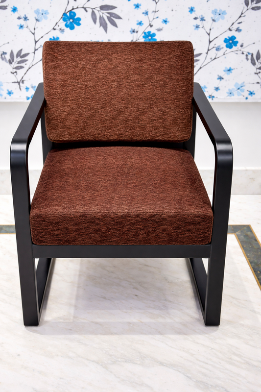 Brown upholstered chair with wrought iron black frame on a light floor with floral wallpaper.